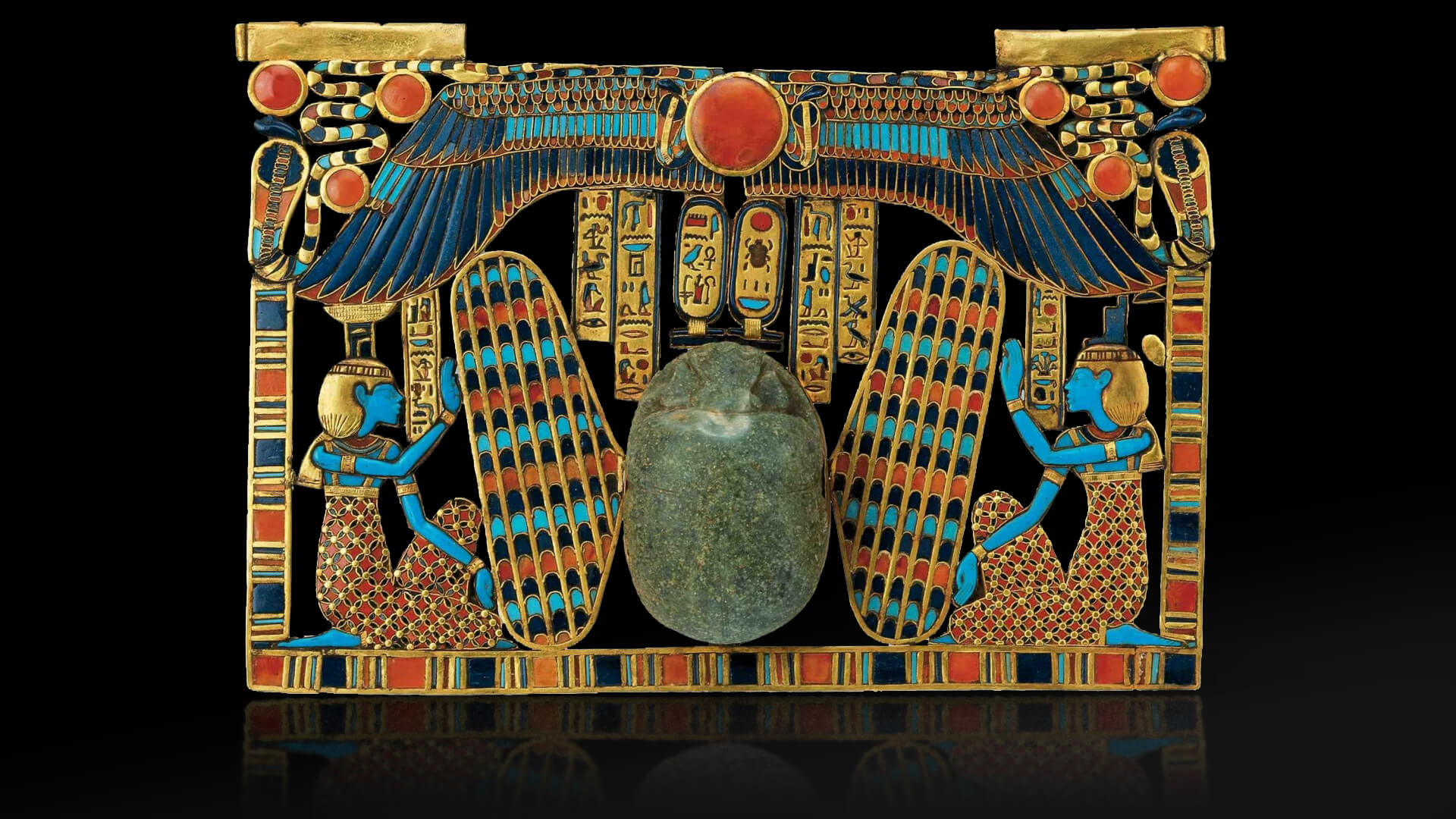 winged, large scarab beetle riding on a sacred barque and flanked by the goddesses Isis and Nephthys. The scarab serves a double function: as a heart scarab and as the ba of the sun god lighting the way to the Tutankhamun. Inlaid pectoral, scarab beetle with Isis and Nephthys. underworld.